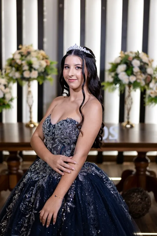 Debutante de vestido azul-marinho bordado em salão decorado com flores