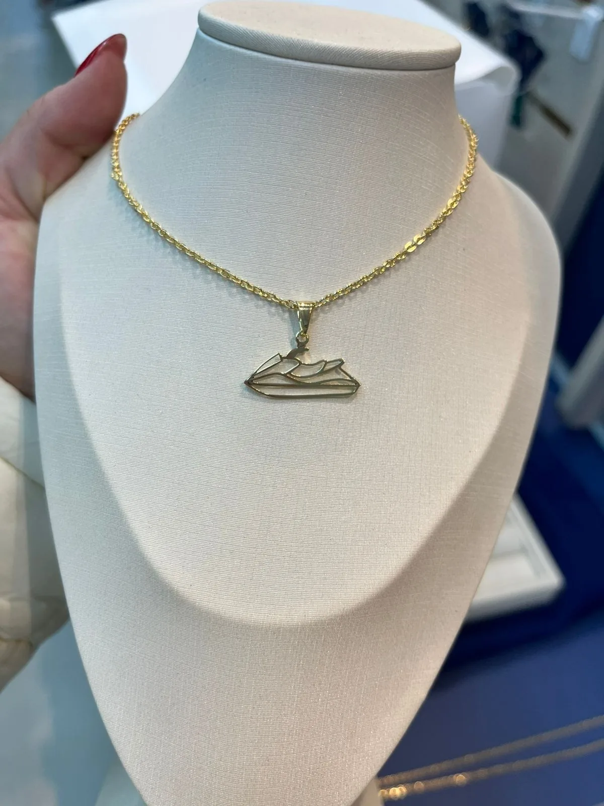 Colar dourado com pingente de jet ski em busto